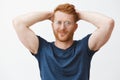 Waist-up shot of confident and relaxed masculine redhead caucasian guy in glasses and blue t-shirt, holding hands behind