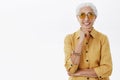 Waist-up shot of elegant good-looking and happy energized senior woman in trendy sunglasses and yellow trench coat