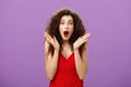 Waist-up shot of excited and amazed expressive elegant adult curly-haired woman with red lipstick in evening luxurious