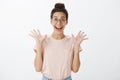 Waist-up shot of excited happy and delighted young beautiful nerdy woman with messy bun and glasses raising palms in joy Royalty Free Stock Photo