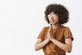 Waist-up shot of focused relaxed and calm attractive young dark-skinned female in glasses with afro hairstyle standing Royalty Free Stock Photo