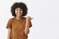 Waist-up shot of friendly good-looking optimistic dark-skinned teenage girl with afro hairstyle in stylish brown t-shirt