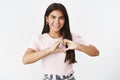 Waist-up shot of friendly sincere and kind young cute indian teenage female showing heart gesture against chest and