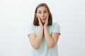 Waist-up shot of funny and emotive playful girl with cute flicked ear holding palms on cheeks folding lips from interest Royalty Free Stock Photo