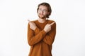 Waist-up shot of guy having troubles with decision crossing arms over body and pointing sideways smirking and frowning Royalty Free Stock Photo