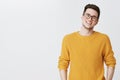 Waist-up shot of happy and delighted handsome young man in glasses and yellow sweater tilting head, smiling and laughing Royalty Free Stock Photo