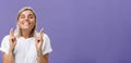 Waist-up shot of hopeful optimistic attractive stylish woman in white t-shirt with tattooed arms winking smiling