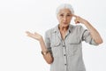 Waist-up shot of irritated smart elderly woman being with son making stupid mistake rolling finger near temple Royalty Free Stock Photo