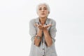 Waist-up shot of kind and cute loving grandmother with gray hair folding lips blowing kiss via air with palms near mouth