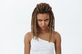 Waist-up shot og angry and moody displeased hateful dark-skinned young female with dreads looking from under forehead