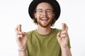 Waist-up shot of optimistic carefree and handsome young bearded guy in glasses and hat laughing out loud with joyful