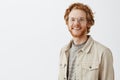 Waist-up shot of pleasant handsome redhead mature guy with beard in transparent glasses and beige jacket over t-shirt