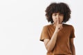 Waist-up shot of serious-looking displeased bossy african american girl in brown t-shirt frowning saying shush showing Royalty Free Stock Photo