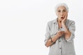 Waist-up shot of shocked and amazed grandmother exploring internet folding lips in amazement and surprise holding hand Royalty Free Stock Photo