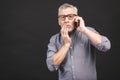 Waist-up shot of shocked senior man with glasses, worry and surprise holding smartphone receiving bad news looking concerned and Royalty Free Stock Photo