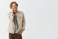 Waist-up shot of shy good-looking and frienly redhead guy with beard and wavy hair touching neck and standing casually