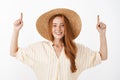 Waist-up shot of sociable and communicative good-looking stylish redhead woman in yellow stylish blouse and straw hat