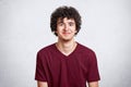 Waist up shot of young attractive guy with curly hair, dresses casual maroon t hirt, free space for your advertisment, models over