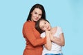 Waist up studio portrait of young mother embracing her daughter. Happy smiling family isolated over pastel blue background. Royalty Free Stock Photo