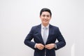 Waistup portrait of young smiling handsome businessman putting on suit jacket looking aside isolated on white