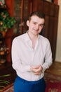 Waistup portrait of young smiling handsome businessman in suit putting cufflinks indoors