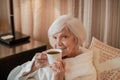 Waistup of a senior woman having morning tea in bed