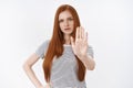 Wait sec hold on. Perplexed displeased angry redhead serious-looking girl raising palm stop prohibition gesture frowning Royalty Free Stock Photo