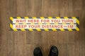 Wait your turn, keep your distance sign on a store floor. Royalty Free Stock Photo