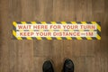 Wait your turn, keep your distance sign on a store floor. Royalty Free Stock Photo