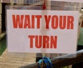 Wait Your Turn sign in red lettering