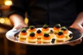 Waiter with appetizers with red and black caviar on plate close-up. Celebration event, party or wedding reception