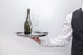 A waiter / butler carrying an silver tray with a bottle of champagne and two glasses Royalty Free Stock Photo