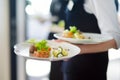 Waiter carrying plates with meat dish on some festive event