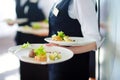 Waiter carrying plates with meat dish on some festive event Royalty Free Stock Photo