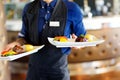 Waiter carrying plates with meat dish on some festive event Royalty Free Stock Photo