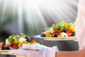 Waiter, carrying three plates with a rich salad at syny day Royalty Free Stock Photo