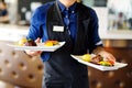 Waiter carrying two plates with meat dish on some festive event Royalty Free Stock Photo