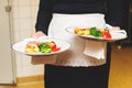 Waiter carrying two plates with meat dish Royalty Free Stock Photo