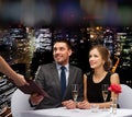 Waiter giving menu to happy couple at restaurant