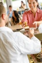 Waiter giving woman cake plate at cafe