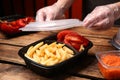 Waiter in gloves closing container with fresh prepared meal at wooden table, closeup. Food delivery service