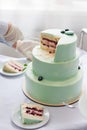 A waiter in gloves cuts a dusty green berry wedding biscuit cake