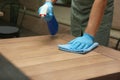 Waiter in gloves disinfecting table at outdoor cafe, closeup
