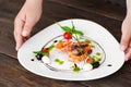 Waiter hands put plate with shrimps on dark table