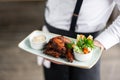 The waiter is holding a plate chicken wings grill. Barbecue restaurant menu, a series of photos of different meats Royalty Free Stock Photo