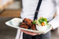 The waiter is holding a plate chicken wings grill. Barbecue restaurant menu, a series of photos of different meats Royalty Free Stock Photo