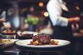 Waiter holding a plate with grilled beef steak with roasted vegetables on a side. Serving fancy food in a restaurant Royalty Free Stock Photo