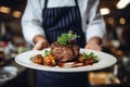 Waiter holding a plate with grilled beef steak with roasted vegetables on a side. Serving fancy food in a restaurant Royalty Free Stock Photo