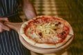 A waiter holds a plate of tasty food. Italian cuisine in restaurant, Pizza with meat, olives and mushrooms, french fries Royalty Free Stock Photo