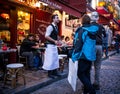 Waiter invites couple into his restaurant on Montmartre in Paris